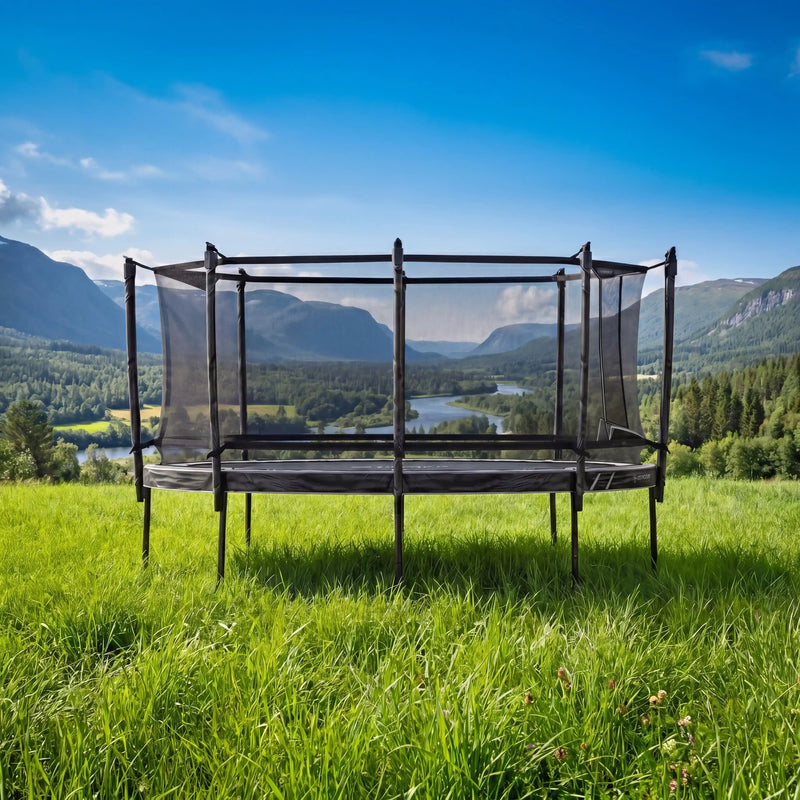 North Oval Trampoline in a grassy field with a scenic view of mountains and a river.