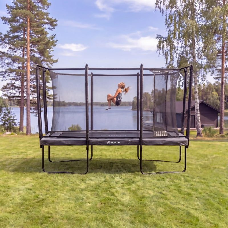 North Pioneer Trampoline in a grassy area with trees and a lake in the background