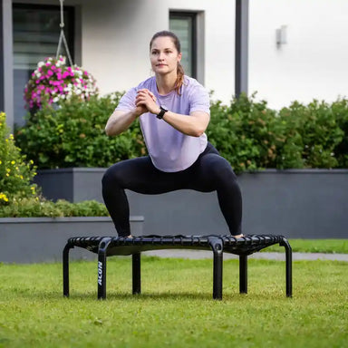 Woman-performing-squat-on-ACON-rebounder-in-garden