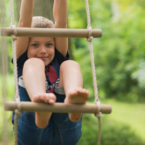 a-young-boy-climbing-up-a-knotted-climbing-rope-on-a-wooden-swing-set-in-a-sunny-backyard