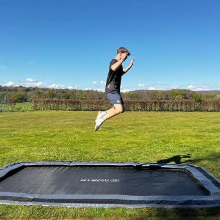 adult-jumping-on-north-17ft-x-12ft-rectangular-inground-trampoline-in-large-garden