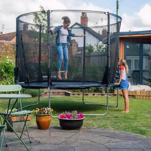 adult-jumping-on-plum-spacezone-trampoline-while-child-watches