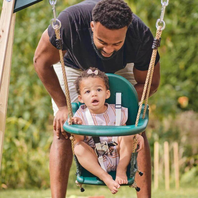 adult-standing-behind-toddler-in-green-bucket-swing-on-wooden-playcentre