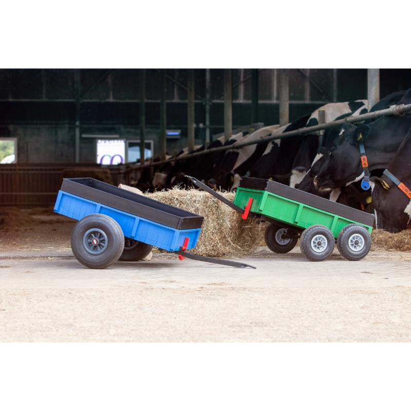 blue-and-green-tipping-pedal-go-kart-trailers-beside-hay-in-a-cow-barn