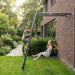 boy-climbing-wall-mounted-frame-while-girl-swings-in-backyard-garden
