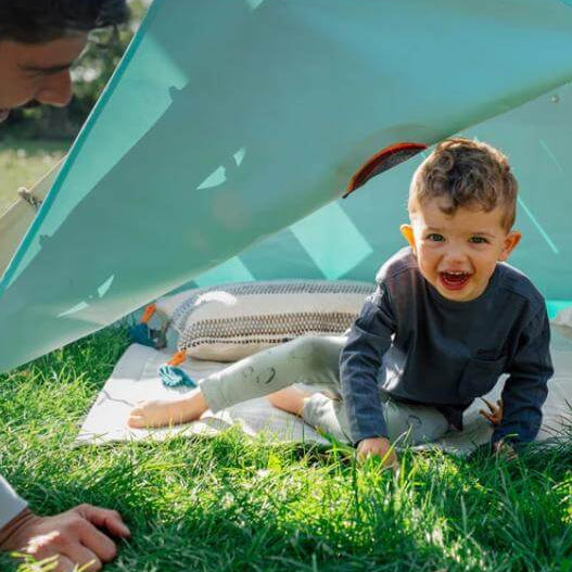 child-crawling-out-of-triangular-play-tent-with-adult-beside-entrance