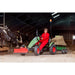 child-driving-a-green-berg-pedal-tractor-with-a-hay-trailer-inside-a-cow-barn