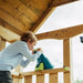 child-looking-through-telescope-on-plum-roofed-wooden-play-tower