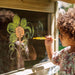 child-painting-flower-on-window-of-plum-discovery-nature-play-hideaway_1