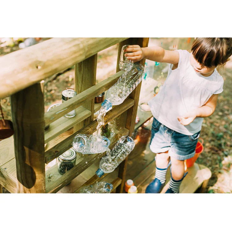 child-pouring-water-through-bottles-on-plum-discovery-mud-pie-kitchen