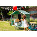 child-pushing-vintage-toy-pram-towards-teal-wooden-playhouse-in-garden
