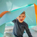 child-sitting-inside-play-tent-holding-blue-fabric-door-flap
