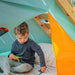 child-sitting-inside-triangular-play-tent-with-orange-door-flap