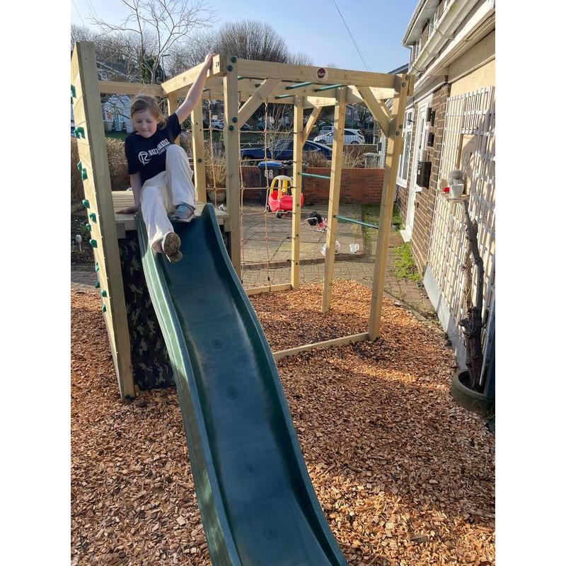 child-sitting-on-wooden-climbing-cube-platform-above-camo-den