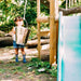 child-standing-by-wooden-playcentre-with-bucket-pulley-and-green-slide