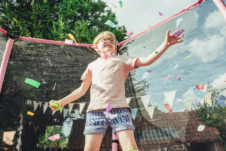 child-throwing-confetti-inside-pink-garden-trampoline