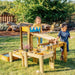 children-playing-with-a-wooden-water-run-activity-set-in-a-garden