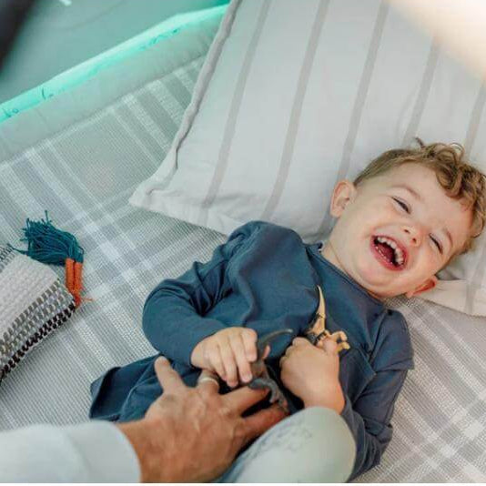 close-up-of-laughing-child-lying-on-cushions-inside-play-tent