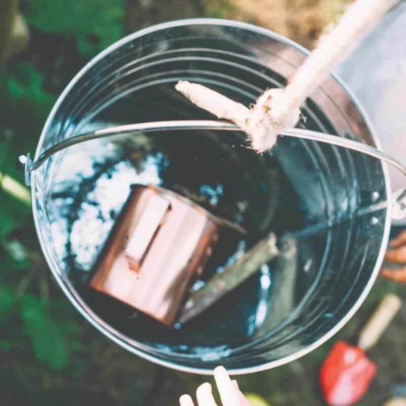 close-up-of-metal-play-bucket-filled-with-water-and-copper-cup