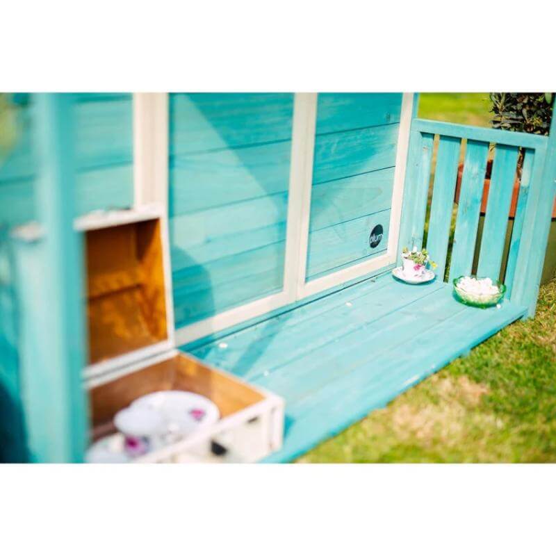 close-up-of-teal-playhouse-veranda-floor-with-tea-set-and-open-storage-box