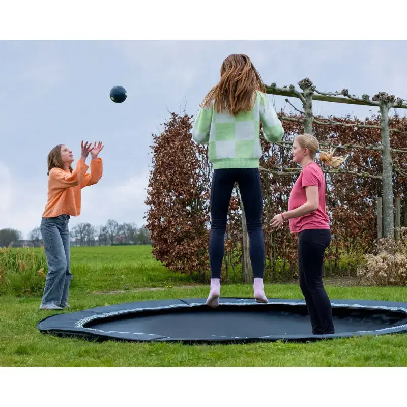 exit-interra-ground-level-trampoline-305cm-with-family-playing-with-bush-in-the-background