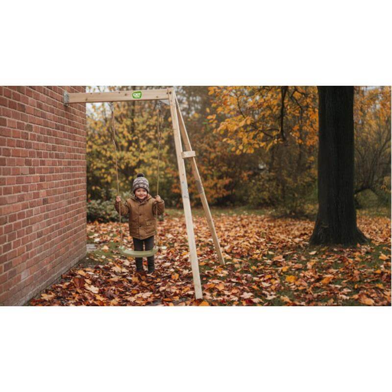 exit-toys-silvi-wooden-swing-set-with-child-swinging-beside-brick-wall-in-autumn