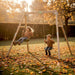exit-toys-silvi-wooden-swing-set-with-two-children-swinging-on-autumn-garden-lawn