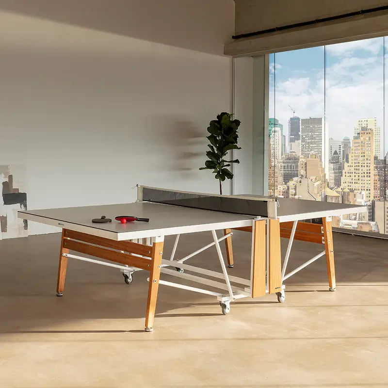full-view-of-rs-barcelona-foldable-ping-pong-table-indoor-setup-with-high-rise-buildings-in-the-right-side-background