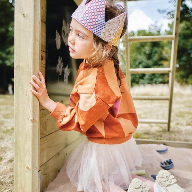 girl-playing-beside-wooden-lookout-tower-chalkboard-and-sand-area