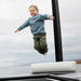 little-boy-jumps-acon-x-triangle-block-with-black-trampoline-post-in-the-background