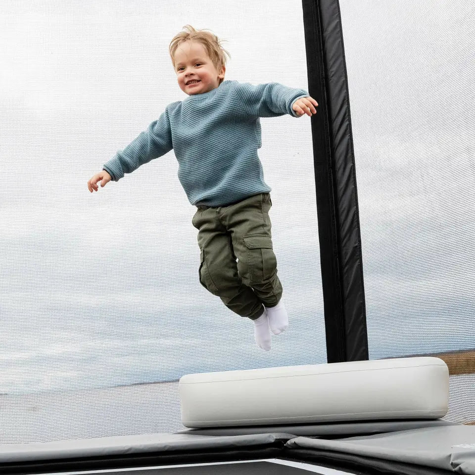 little-boy-jumps-acon-x-triangle-block-with-black-trampoline-post-in-the-background