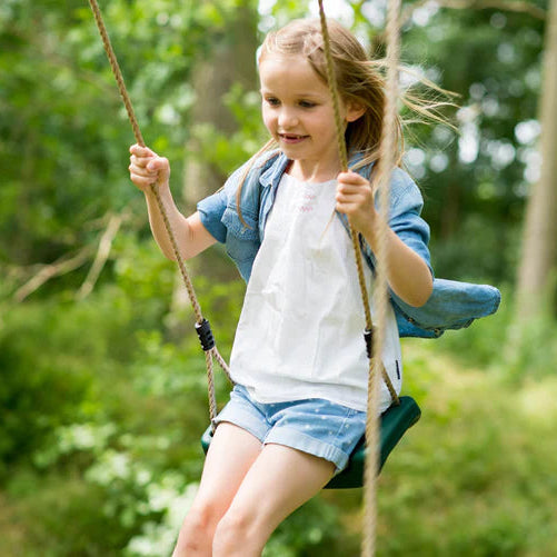 playing-together-on-a-plum-gibbon-wooden-swing-set-with-pink-accents-in-a-green-garden-setting