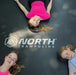 three-girls-lying-on-north-trampoline-jump-mat-with-logo-visible