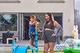 three-young-children-happily-playing-with-the-outdoor-wooden-water-park-splash-station-in-a-garden-setting