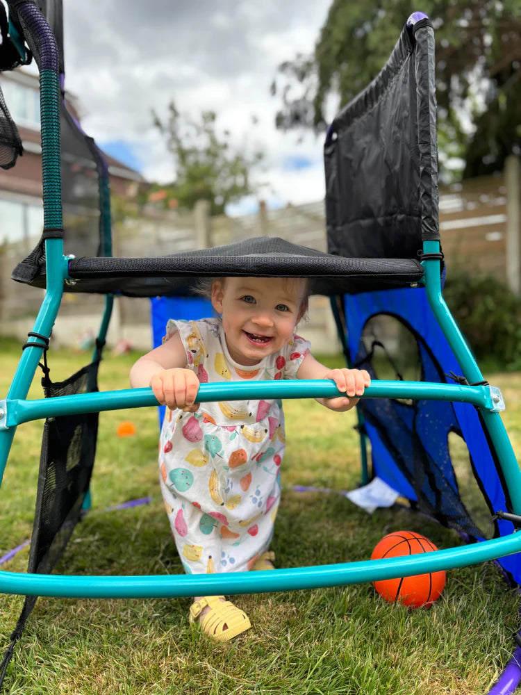 toddler-standing-beneath-mini-play-centre-frame-on-grass