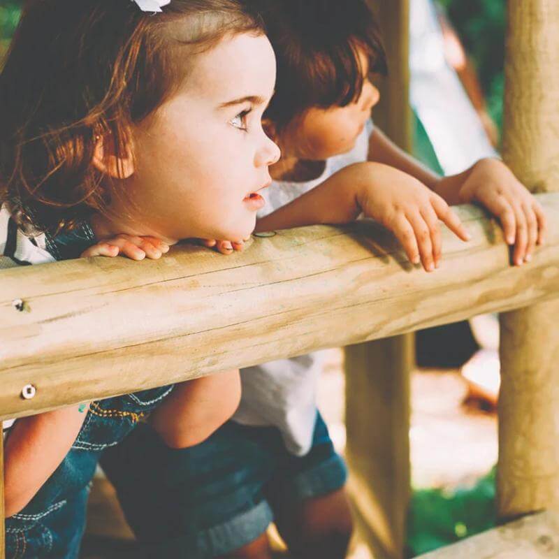 two-children-leaning-over-wooden-playcentre-railing