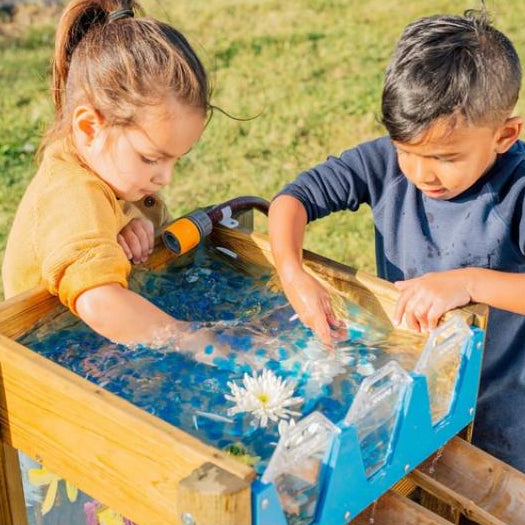 two-children-splashing-at-the-top-water-reservoir-of-a-wooden-water-run
