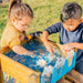 two-children-splashing-at-the-top-water-reservoir-of-a-wooden-water-run