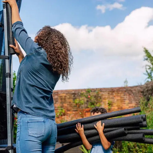 woman-assembling-plum-spacezone-trampoline-enclosure-with-child-holding-pole-covers