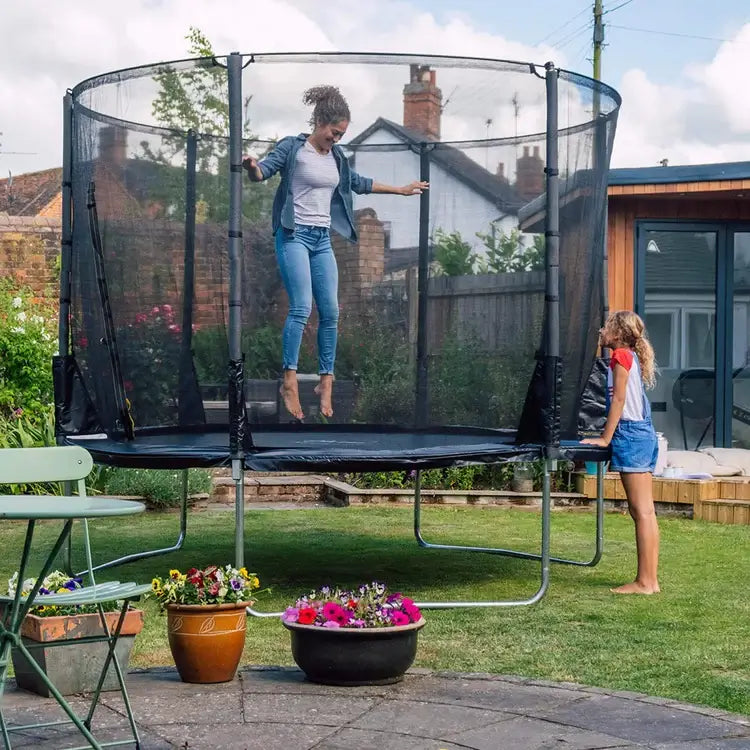 woman-jumping-on-plum-spacezone-ii-evolution-trampoline-with-child-watching
