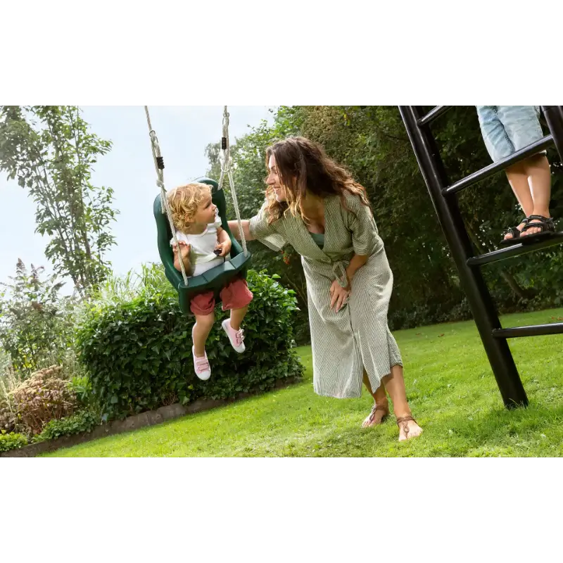 woman-pushing-young-child-in-green-bucket-swing-on-outdoor-play-frame-in-garden