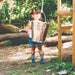 young-child-holding-metal-bucket-beside-wooden-playcentre-in-woods