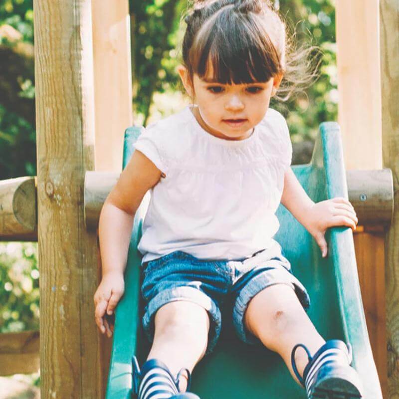young-child-sitting-on-green-slide-on-wooden-playcentre